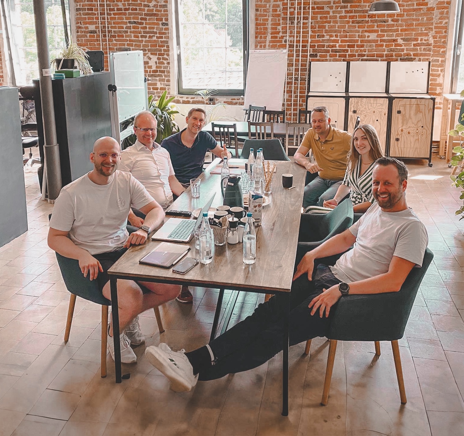 Das Workshopteam von brose und Bytabo sitzt an einem Tisch und brainstormt Nutzungsmöglichkeiten für KI in der Zukunft der Automobilindustrie.